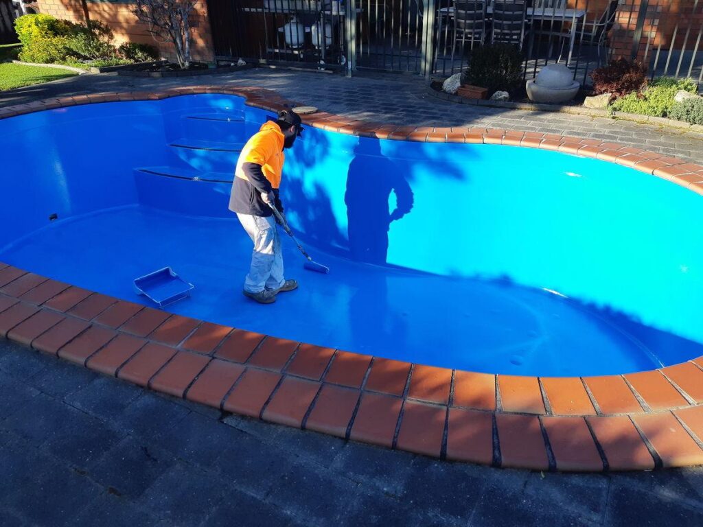 Professional inspecting the surface of a concrete swimming pool before recoating in Perth, Western Australia.