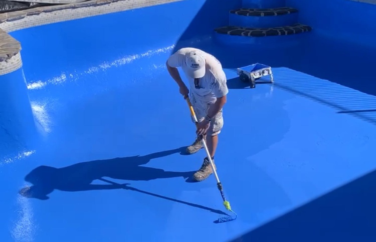 Swimming pool coating contractor applying protective pool coating to a concrete swimming pool in Perth