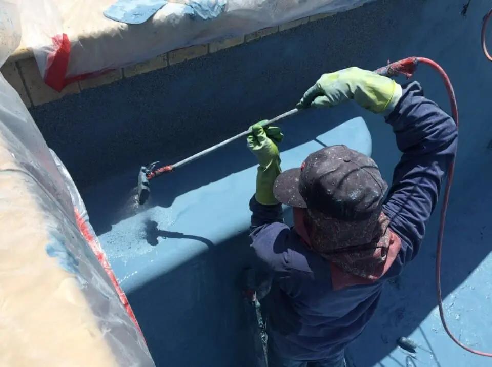 Professional applying a protective coating to a concrete swimming pool in Perth, Western Australia