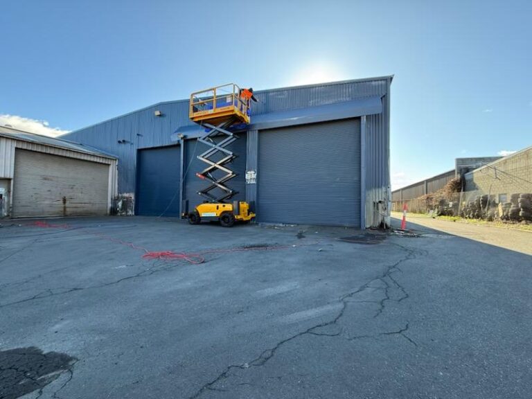 Commercial painter using a scissor lift on an industrial warehouse