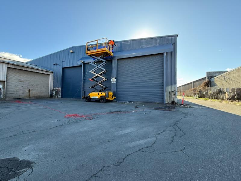 Commercial painter using a scissor lift on an industrial warehouse