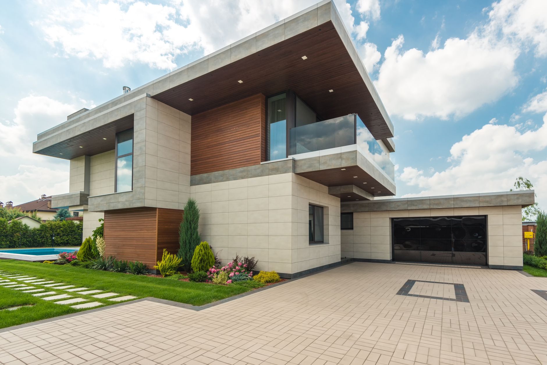 Contemporary luxury house with a sleek design, lush garden, and blue sky, how driveway coatings are applied to concrete