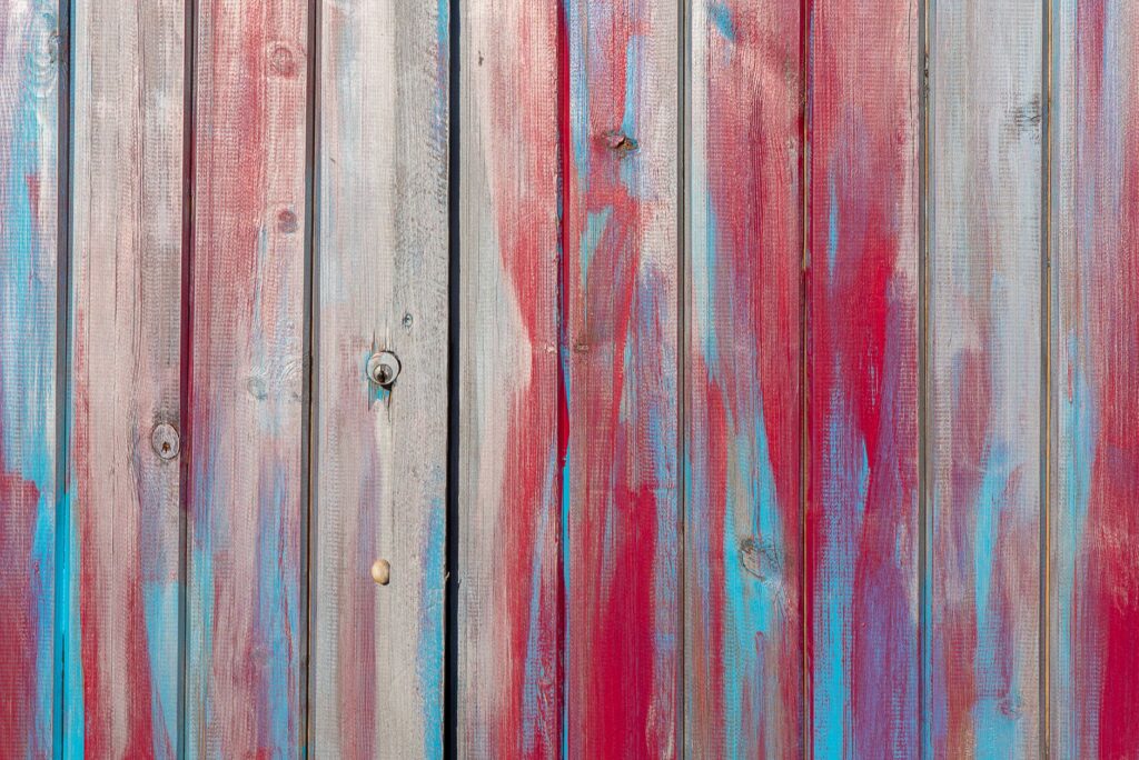 Close-up of a colorful wooden fence with artistic red and blue paint strokes.