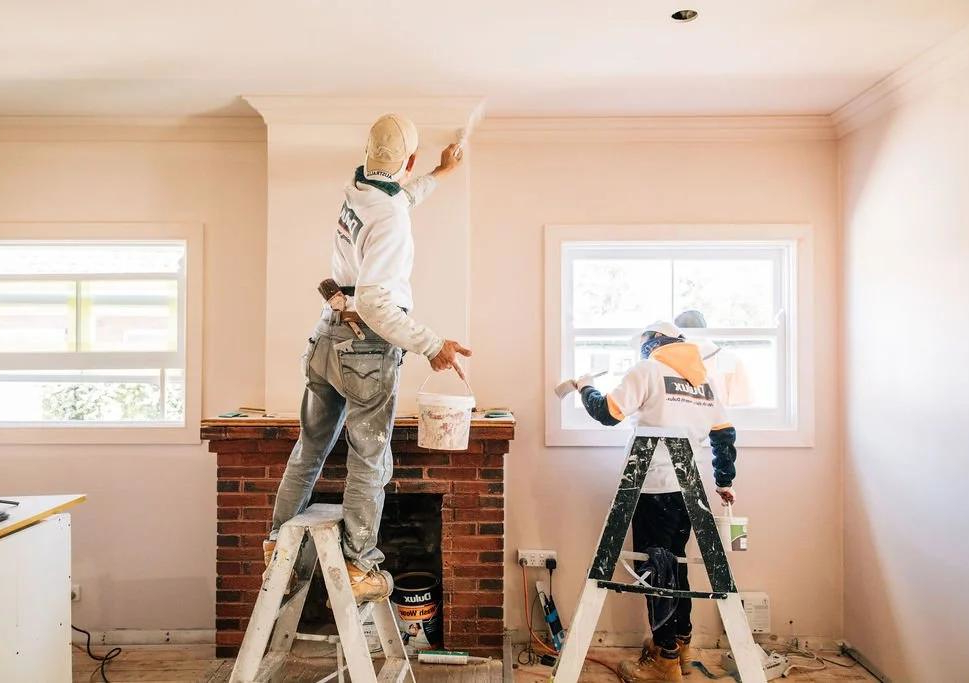 Interior house painter applying fresh paint to a living room wall in a residential property
