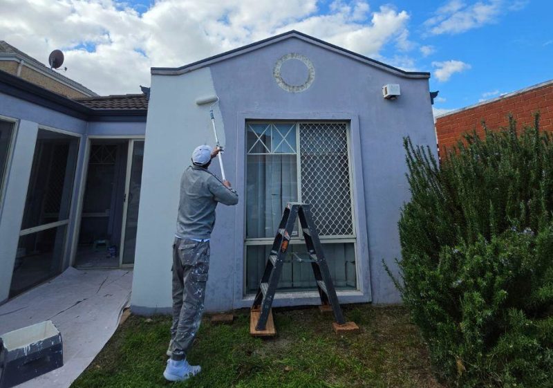 Exterior house painter in Perth applying paint with a roller to an exterior wall of a residential home.