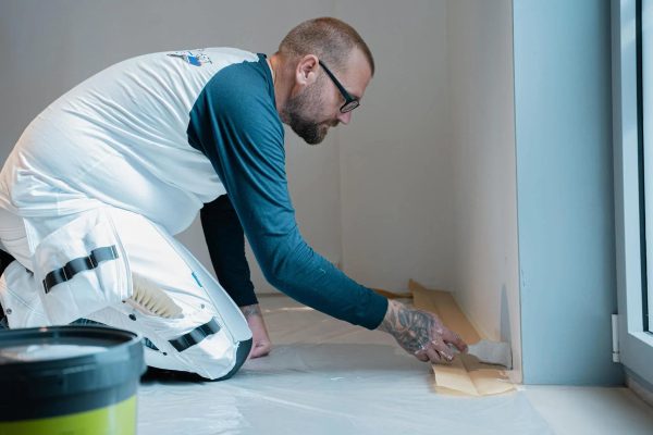 Professional painter preparing and painting an interior wall in Perth