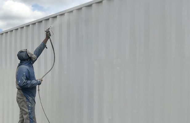 Worker repainting the exterior of a shipping container