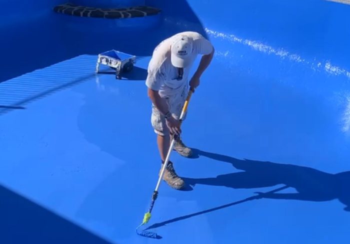 Painter applying a coating inside a concrete swimming pool in Perth
